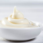 Ceramic white gravy boat with mayonnaise on white background