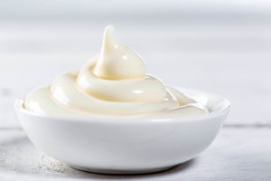 Ceramic white gravy boat with mayonnaise on white background